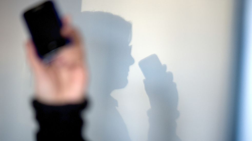 Eine Person telefoniert mit ihrem Mobiltelefon an der Wand zeichnet sich ihr Schatten ab. Foto: Arno Burgi/dpa-Zentralbild/dpa