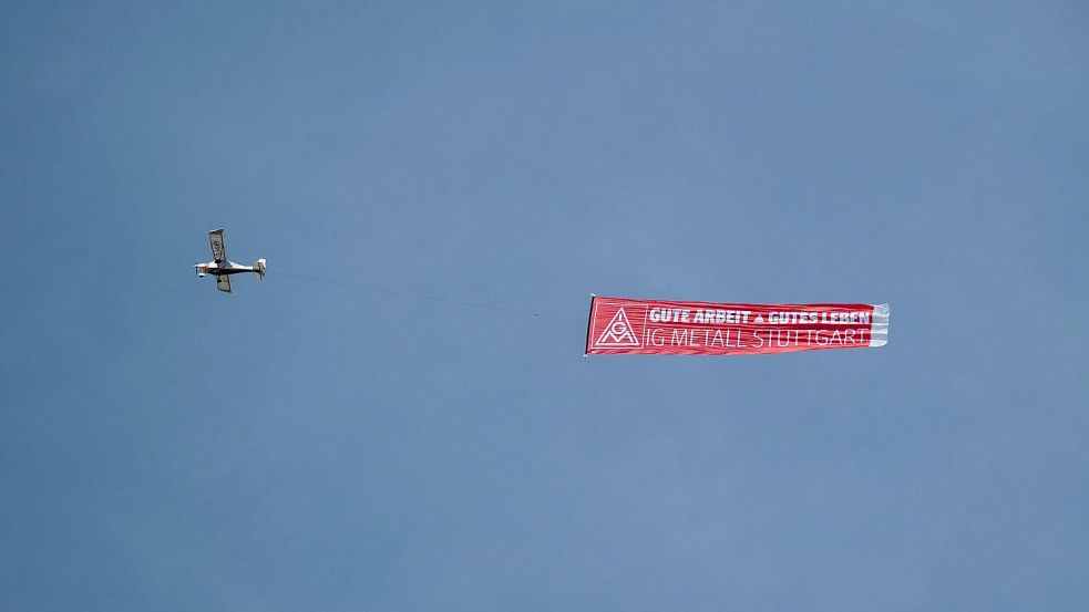 Ein Flugzeug mit einem IG-Metall-Banner fliegt über das Porsche-Stammwerk in Zuffenhausen. Foto: Marijan Murat/dpa