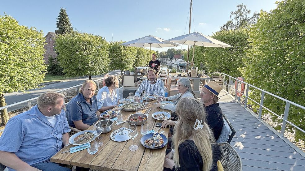 In der dritten Folge der ostfriesischen Lecker-an-Bord-Staffel sitzen Hermann Poppen (von links), Björn Freitag, Klaas Froschauer, Skipper Kai Linnenbrügger, Nadja Poppen, Rieka Poppen und Frank Buchholz gemeinsam am Tisch. Foto: Karin Böhmer