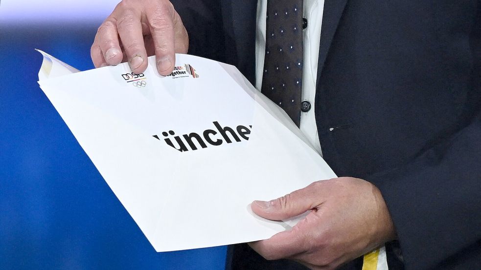 Ups, da war’s schon verraten: Durch eine kleine Panne konnte das Fernsehpublikum schon vor Bundespräsident Steinmeier sehen, dass München für Deutschland um Olympia ins Rennen geht. Foto: dpa/Marijan Murat