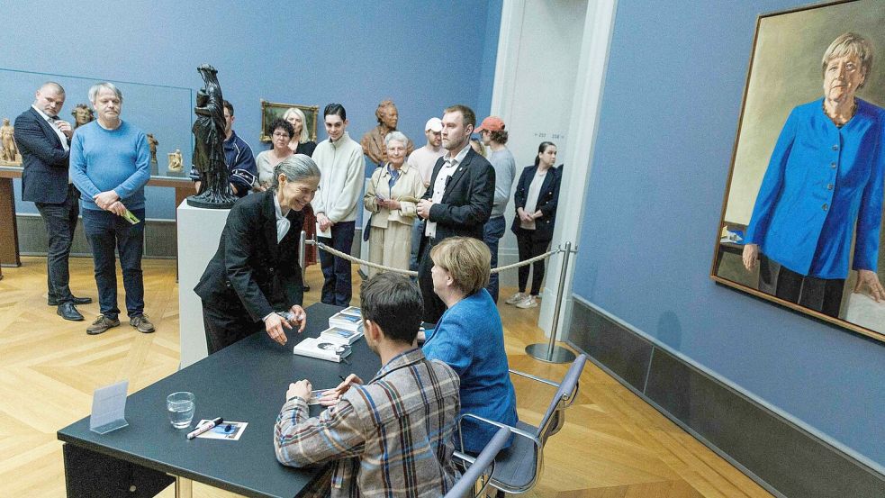 Im Bode-Museum signierte Merkel am Nachmittag Kunstpostkarten gemeinsam mit dem Maler ihres Porträts. Foto: Carsten Koall/dpa