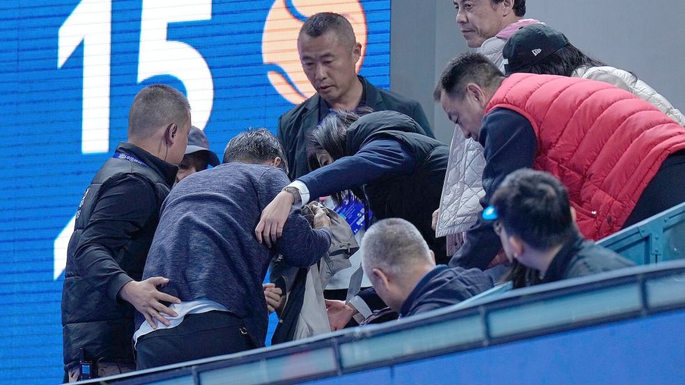 Helfer kümmern sich um einen Mann, der von einem Ball verletzt wurde, den der Russe Medwedew in die Zuschauerränge geschlagen hatte. Foto: Andy Wong/AP/dpa