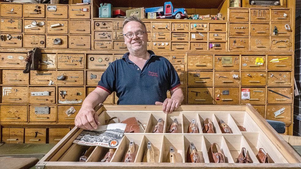 Peter Schmidt steht vor der alten Schrankwand aus dem geschlossenen Eisenwarengeschäft Saathoff aus Remels. Vor ihm ist ein Schaukasten der alten Kinderschuhfabrik Gustav Hoffmann aus Kleve am Niederrhein. Foto: Klaus Ortgies