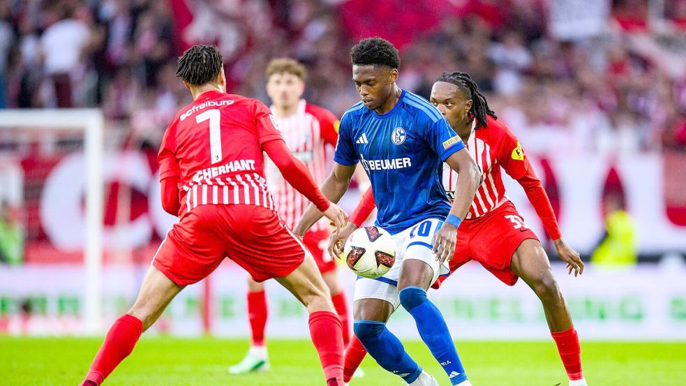 Umzingelt: Schalkes Junior Adamu (M.) gegen Ex-Club Freiburg. Foto: Tom Weller/dpa
