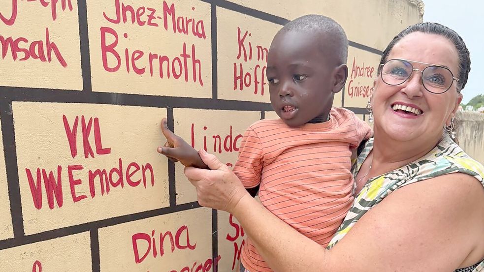 Hinweis auf den Verein „Villa4KidsLife“ (VKL) und das Engagement der Kollegen von VW Emden: Herta Everwien mit Kweku (4) in Ghana, Cape Coast. An dieser Wand werden alle Spender verewigt. Foto: privat