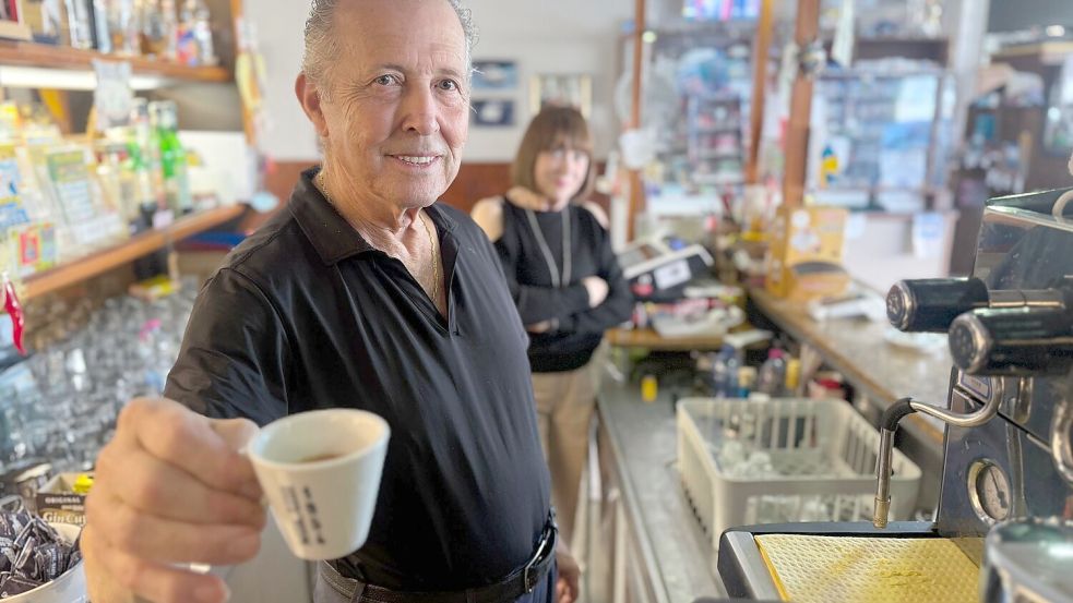 Orlando Paldino zeigt stolz eine Tasse Espresso für 70 Cent. Im Hintergrund steht seine Frau Rosina Furiati. Foto: Christoph Sator/dpa
