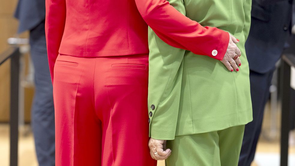 Zwei Abgeordnete der SPD stehen mit roten und grünen Hosenanzügen – passend zur rot-grünen Koalition – im niedersächsischen Landtag. Foto: dpa/Julian Stratenschulte