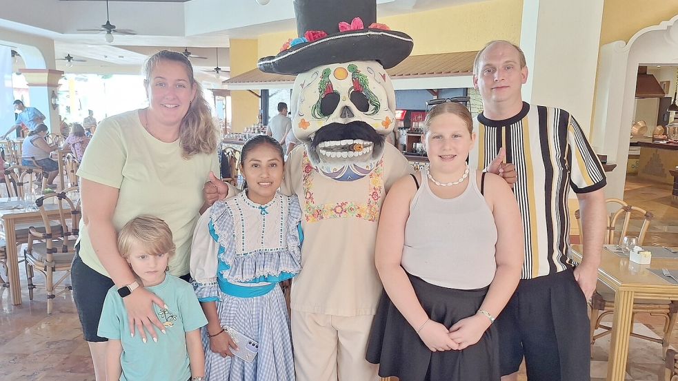 Erinnerungsfoto mit einer Hotelmitarbeiterin und einem Darsteller aus der Dia-de-los-Muertos-Veranstaltung in traditioneller Verkleidung: Jennifer (links) und Mirko (rechts) Tholen mit ihren Kindern Solveigh und Emiljan waren schon zwei Mal in Mexiko, während das Totenfest vorbereitet wird. Foto: privat/Tholen