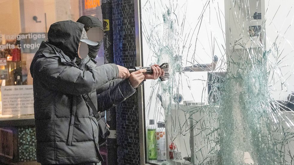 Zwei Männer stehlen durch die eingeschlagene Scheibe eines Waffengeschäft eine Waffe.  Foto: Andreas Arnold/dpa